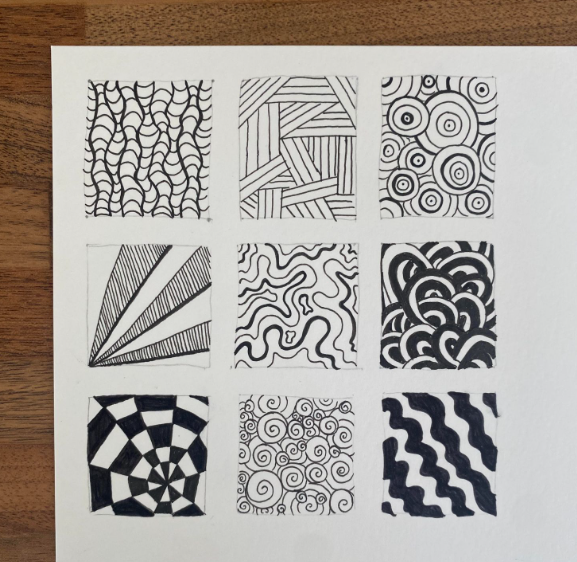 A picture of a sketchbook page with examples of different patterns drawn in pen. Some use straight lines, some are curved, they are all in black and white.